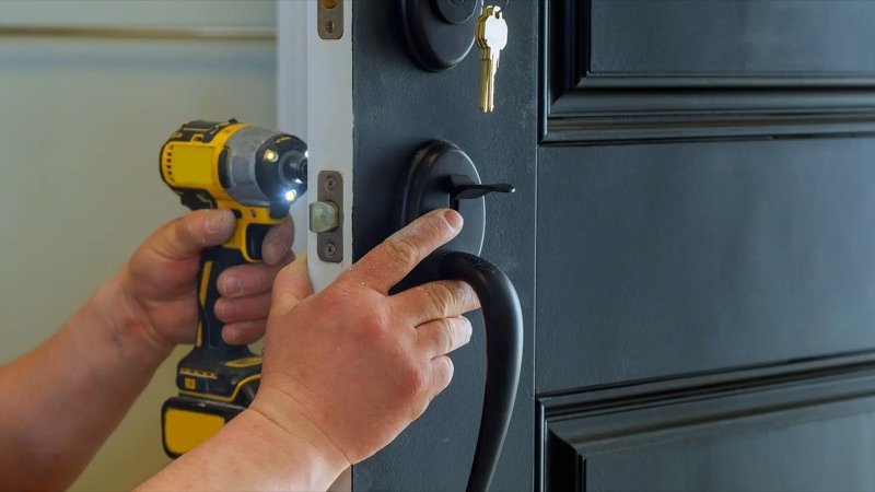 Serrurier Nova remplaçant la serrure d'une porte d'entrée à la visseuse